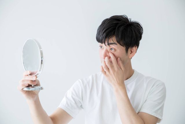 目を鏡でチェックする男性